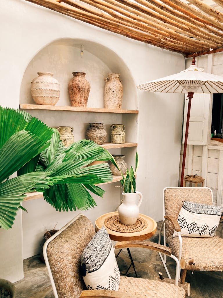 Cozy outdoor seating with boho decor, vases, and tropical plants in a serene setting.