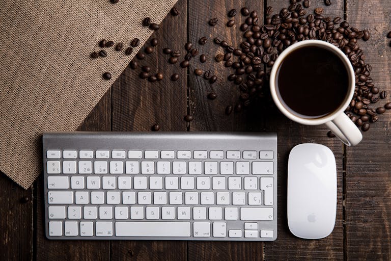 Top view of a coffee cup with keyboard and mouse on a rustic wooden desk.